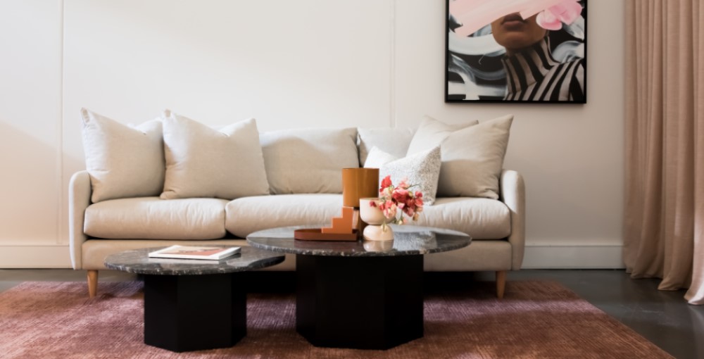 beige sofa with cushions and a paint in the wall